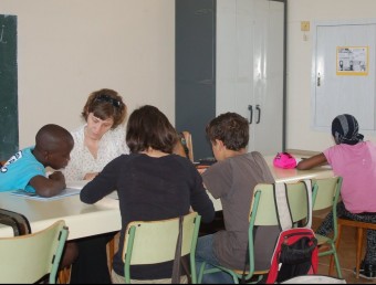 Una voluntària de Càritas ajudant uns alumnes a fer uns treballs d'escola. EL PUNT AVUI