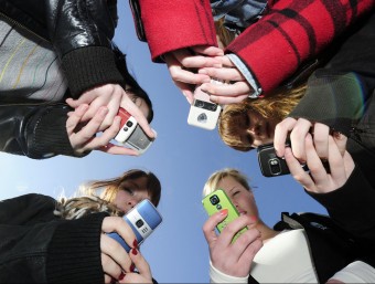 Teenagers playing with their smart phones.  AFP