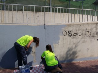 Alguns dels joves de la brigada fent els treballs per netejar les pintades a una de les parets del murs de l'escola bressol municipal. E.F