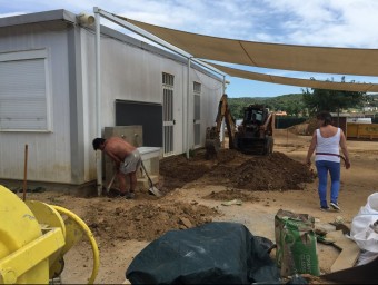A l'esquerra, un operari treballant en una de les zones on s'hi posarà ciment per facilitar l'accés als escolars i mestres J.N