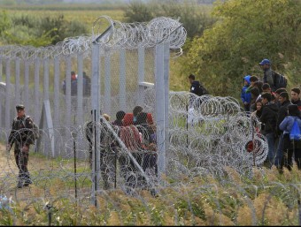 Un grup de persones s'han trobat amb la tanca de filferro vigilada per l'exèrcit hongarès que els ha impedit creuar la frontera des de Sèrbia a Röszke (Hongria) REUTERS