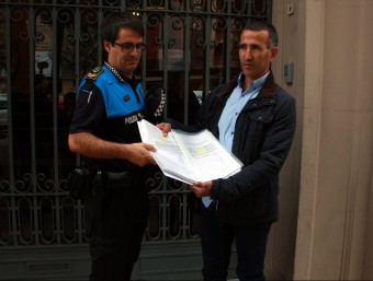 L'alcalde d'Alcarràs, Miquel Serra i el sergent de la policia local del municipi lliurant les signatures ACN