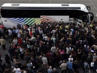 Desenes de persones esperen per pujar en un autobús a l'estació de Sants EFE