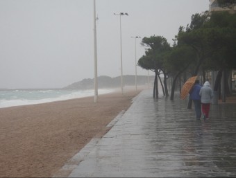Una parella caminant amb dificultat pel passeig marítim de Platja d'Aro pel vent i la pluja, ahir al migdia T. TÀPIA / ACN