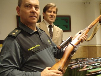 El tinent coronel Jorge Cumba empunya una de les armes davant del subdelegat Juan Manuel Sánchez Bustamante i dertall d'alguna de les 217 armes comissades a Camprodon. TURA SOLER