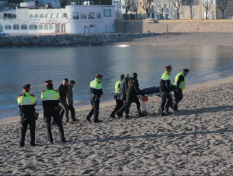 Els mossos i els funeraris retiren el cos del banyista trobat mort a la platja de Sant Feliu de Guíxols. EMILI AGULLÓ