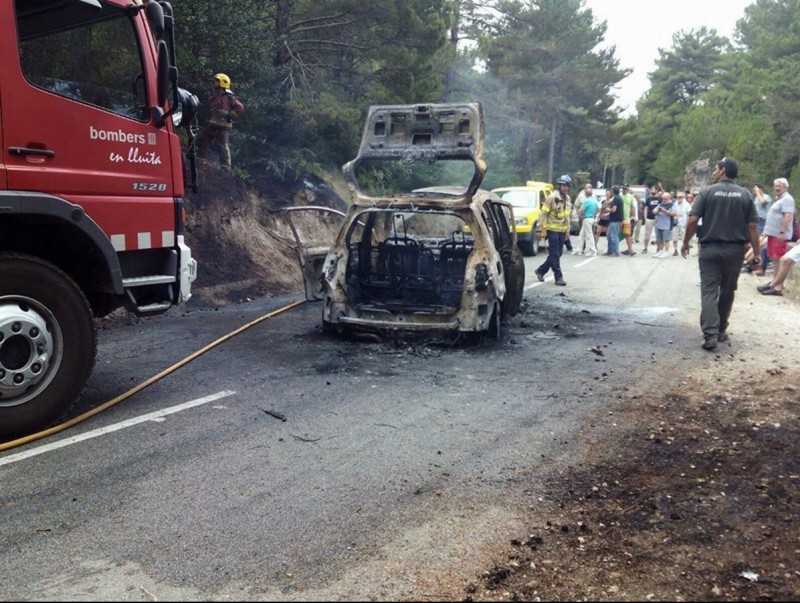 Pla general del cotxe incendiat al Portell al terme d'Alfara de Carles, amb els cossos d'emergència. REFUGI MONT CARO
