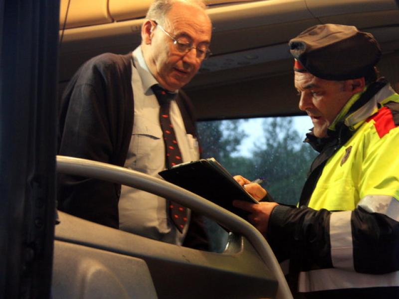Un agent dels Mossos d'Esquadra repassa la documentació amb el conductor d'un dels busos. ACN