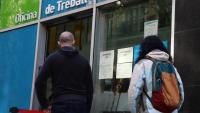Dues persones esperen torn al carrer abans d’entrar en una Oficina de Treball de la Generalitat