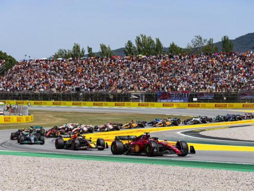 Verstappen encalça Leclerc en el primer revolt, amb una pancarta dels seus seguidors en segon terme