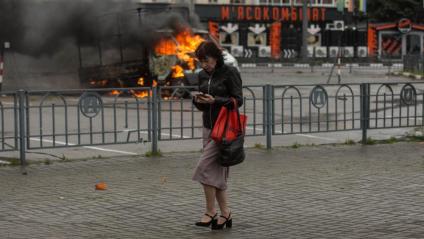 Una dona al davant d’una furgoneta en flames per una bomba a Khàrkiv