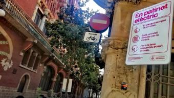 Un rètol amb advertències sobre com han de circular els patinets, al carrer Sant Pere Més Alt de Barcelona