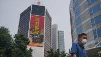 Un home, passa per davant d’un edifici amb un anunci militar a Pequín