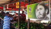 Una persona compra en un mercat davant una imatge de Fidel Castro, a l’Havana