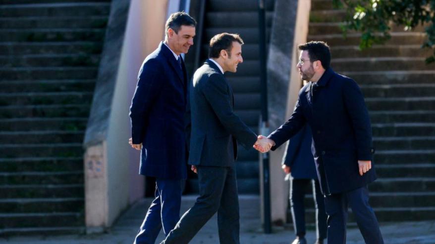 A sota, Pere Aragonès saludant Emmanuel Macron davant la mirada de Pedro Sánchez