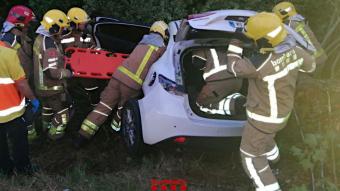 Els Bombers rescatant els ocupants del cotxe accidentat a Flaçà
