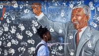 Una noia sud-africana passa per davant d’un mural amb la imatge de Nelson Mandela, a Johannesburg